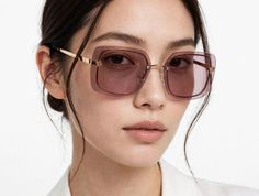Woman with dark hair wearing pink-tinted sunglasses and a white shirt