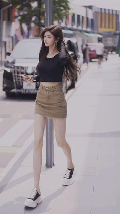 Woman with long hair wearing a crop top and mini skirt walking on a street