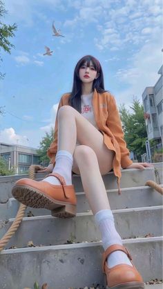 Woman in an orange jacket and mary jane shoes sitting outdoors