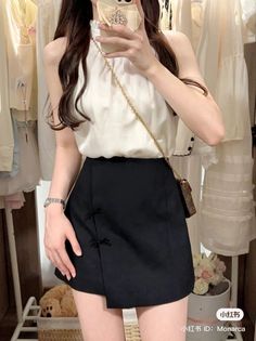 Woman in a white halter neck top and black mini skirt holding a phone