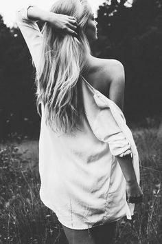 Woman with long blonde hair in a white shirt, seen from behind in black and white