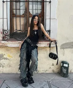 Person with long hair wearing cargo pants and a black top outdoors