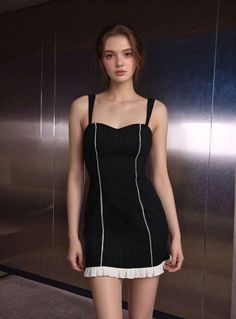 Woman in a black pinstripe dress with ruffle trim standing indoors