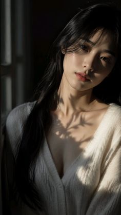 Woman with long black hair in a white cardigan with plant shadows on her chest