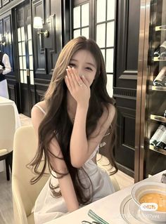 Woman with long hair in a white dress smiling at a restaurant table