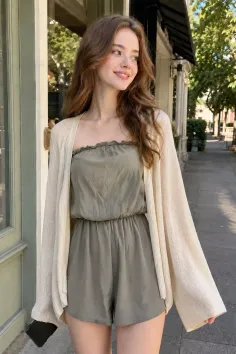 Woman in a green romper and cream cardigan on a sunny street