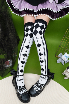 Legs wearing black and white thigh-high socks with playing card symbols and black mary jane shoes