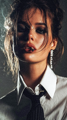 Woman in a white shirt and black tie smoking with dramatic lighting