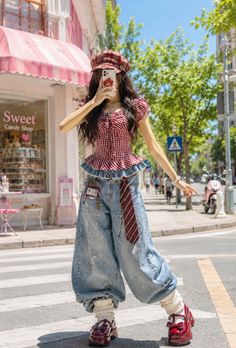 Woman in a plaid top, baggy jeans, and beret hat taking a selfie on a street