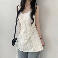Woman with long black hair wearing a white lace top and jeans
