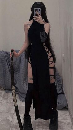 Person in a black dress with exposed skin and a katana, taking a mirror selfie