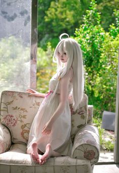 Person with long white hair and an angel halo sitting on a floral armchair