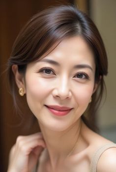 Woman with brown hair and gold earrings smiling in a soft-lit portrait