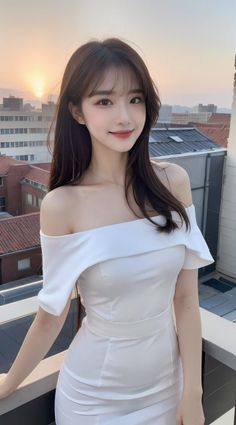 Woman in a white off-shoulder dress on a balcony at sunset