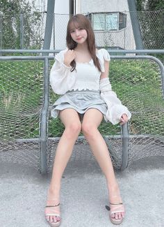 Woman in a white top and mini skirt sitting outdoors