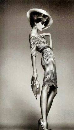 Woman in a gingham dress and wide brim hat posing with a handbag