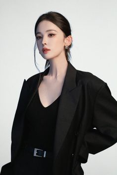 Woman in a black blazer and v-neck top with her hair in a ponytail