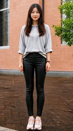 Woman in a grey hoodie and black pants standing outdoors