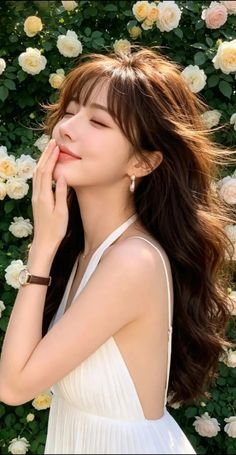 Woman with long hair in a white dress posing outdoors with roses