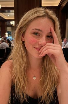 Blonde woman with freckles and a necklace, smiling indoors
