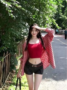 Woman in a red crop top and plaid shirt with braids outdoors