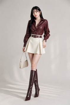 Woman with long black hair wearing a leather shirt and mini skirt with knee-high boots