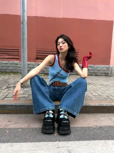 Woman in wide leg jeans and platform shoes sitting on a curb