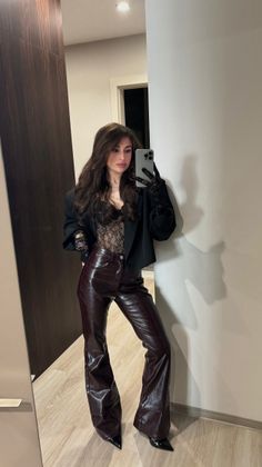 Woman in a lace bodysuit and leather pants taking a mirror selfie