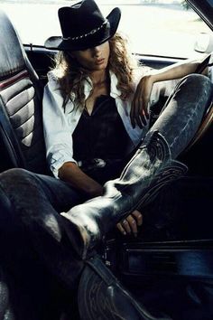 Woman in a cowboy hat and boots sitting in a car