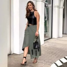 Woman in a black crop top and asymmetrical skirt walking outdoors