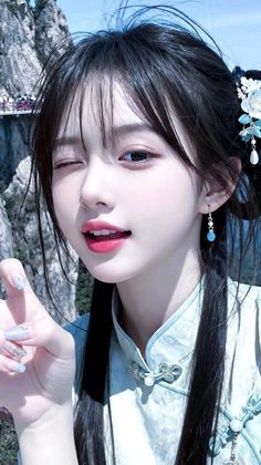 Woman in traditional Chinese clothing winking with a mountain background