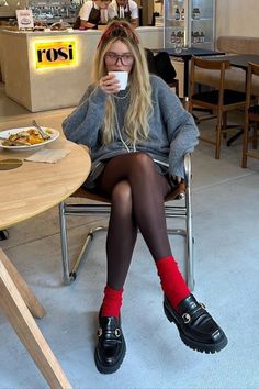 Woman with long blonde hair and glasses drinking coffee in a cafe