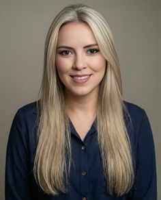 Woman with long blonde hair wearing a navy blue shirt against a neutral background