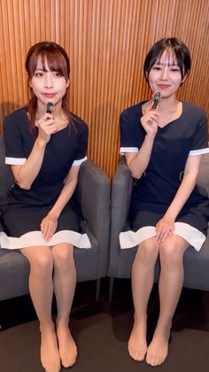 Two women in navy dresses and tights sitting indoors