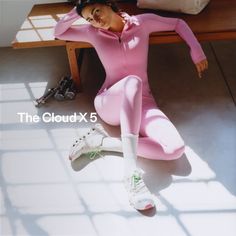 Woman in pink activewear and athletic shoes sitting on a concrete floor