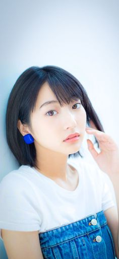 Woman with short black hair and blue earrings wearing a white t-shirt and denim skirt