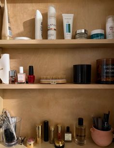 Bathroom cabinet with various skincare, makeup, and personal care products on wooden shelves