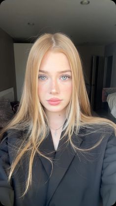 Woman with blonde hair and blue eyes wearing a black blazer indoors