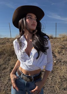 Woman in a cowboy hat and white shirt with jeans outdoors