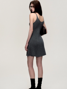 Woman in a gray dress and glasses looking over her shoulder