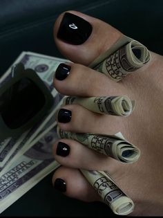 Foot with black pedicure and rolled money between the toes