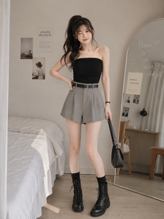 Woman in a black tube top and high-waisted shorts posing indoors