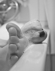 Foot with dark nail polish in a bubble bath, black and white photograph