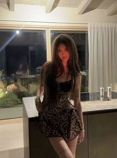 Woman in a leopard print dress posing indoors at night