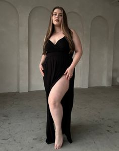 Woman in a black dress with a high slit and exposed cleavage indoors