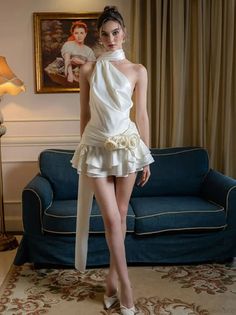 Woman in a white ruffled dress and high heels standing indoors