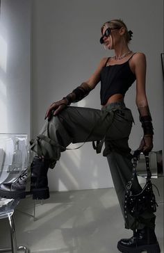 Woman in a black corset top and cargo pants posing indoors