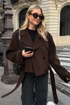 Woman in a brown jacket and sunglasses on a city street