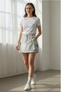 Woman in a white t-shirt and cargo skirt standing indoors
