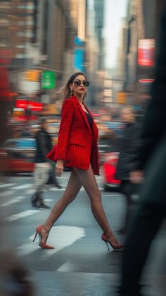 Woman in a red blazer and high heels walking on a busy city street